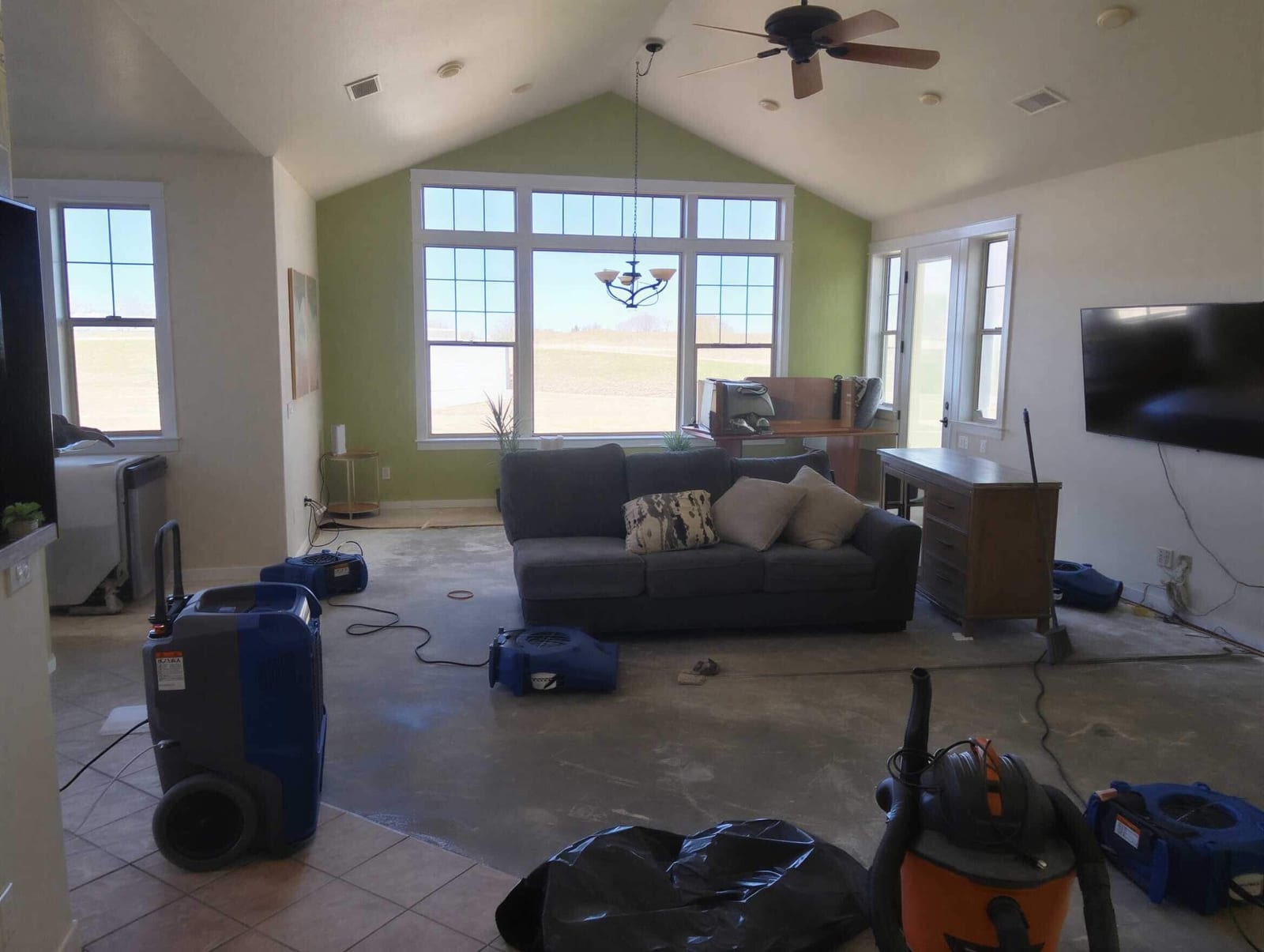An emergency water-damage crew working a flooded living room with extraction and drying gear